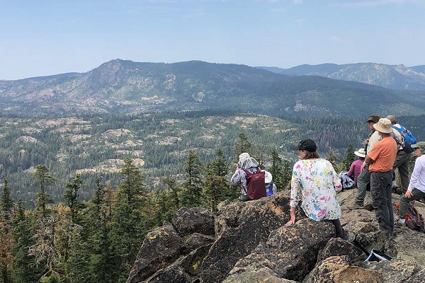 Hikers admire a mountain forest view
