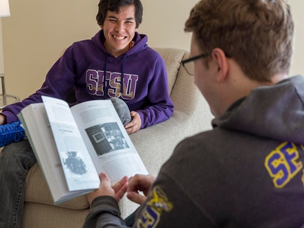 Man holding a book with another man smiling