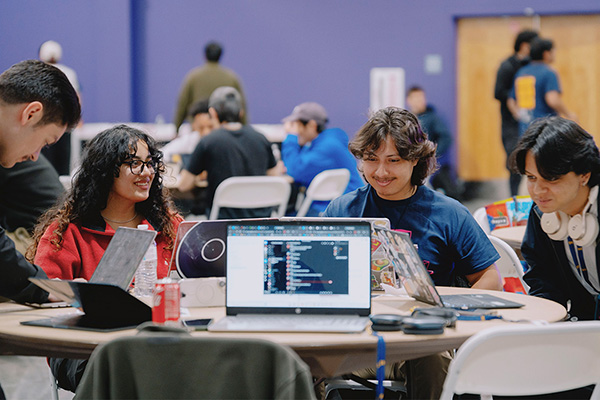 Hackathon participants grouped together working on their laptops