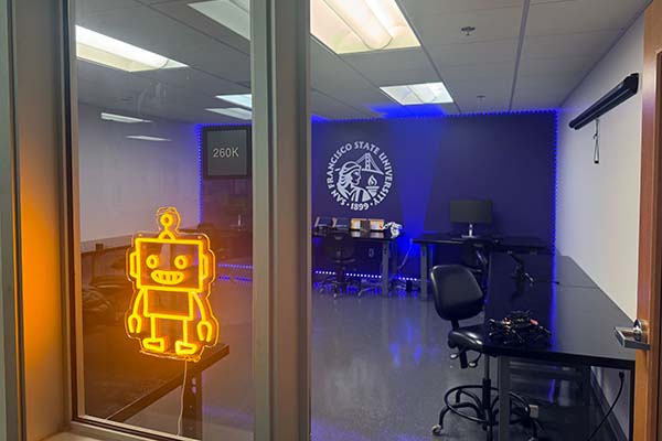 SFSU AI Studio with workspaces and a neon robot in the window.