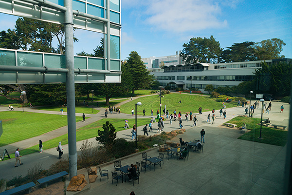 Students walk across a sunny campus quad on their way to class.