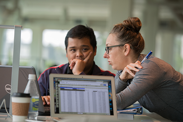 Two people having a discussion with laptop open