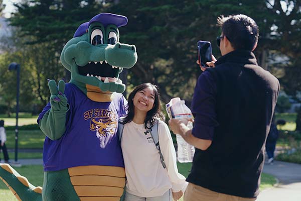 Mascot Alli Gator with a student posing in front of a photographer
