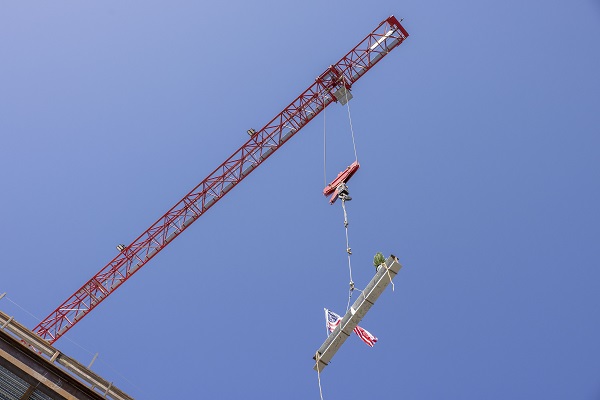 A crane raises the final beam onto the Science and Engineering Innovation Center under construction