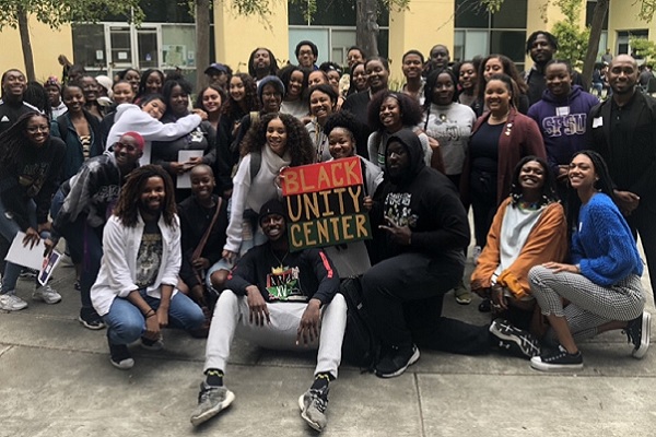 A group of students and staff members gather around a sign saying Black Unity Center