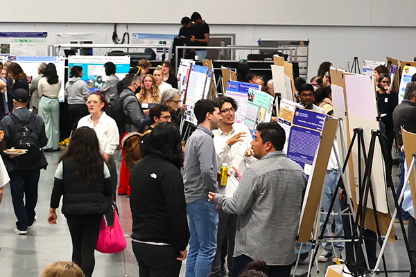 Students and faculty showcase research posters and projects at a large conference.