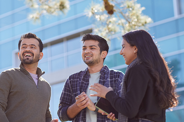 Three SFSU students engaged in a lively conversation outside the J. Paul Leonard Library.