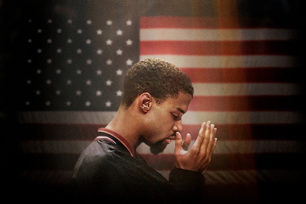 Mahmoud Abdul-Rauf praying in front of a flag