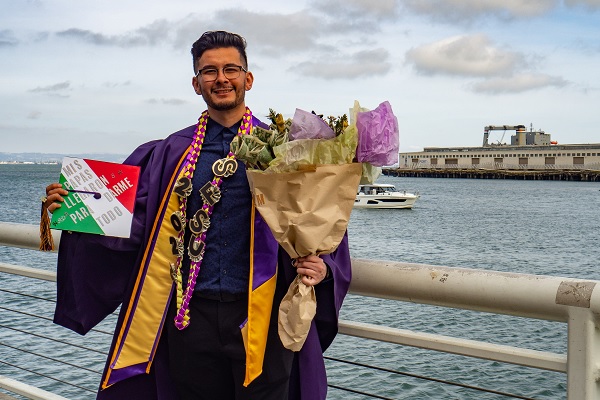 A Latinx student poses in his graduation regalia