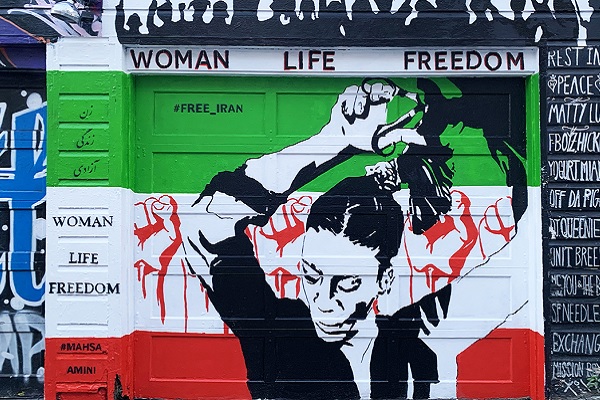 A mural depicts a woman and raised fists against the backdrop of the Iranian flag