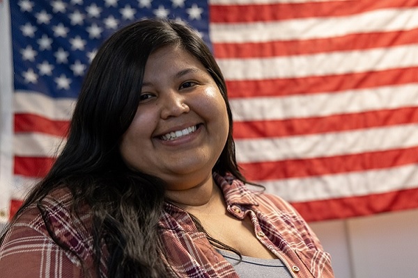 Briana Torres stands in front of a U.S. flag