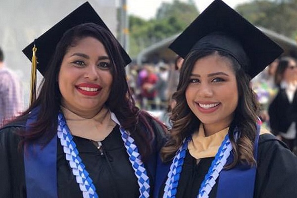 Two smiling women in graduation regalia