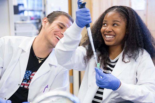Two students in lab coats laugh