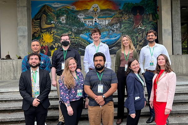 SFSU student researchers posing for a photo on outdoor steps in front of a colorful mural.