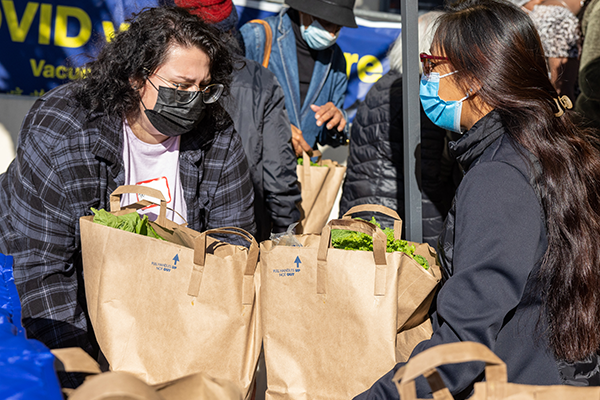 College Corp fellow handing out food support bags