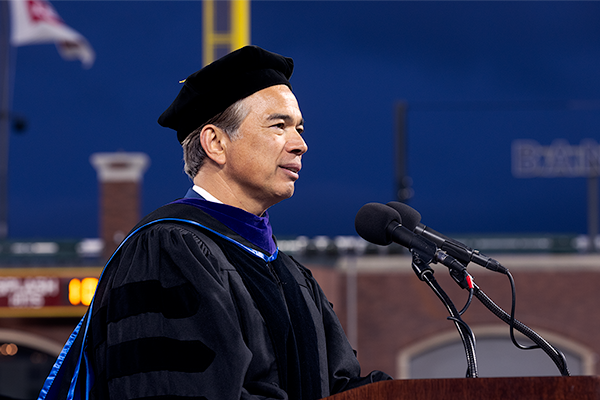 Rob Bonta speaks behind a podium on the platform at SFSU Commencement at Oracle Park