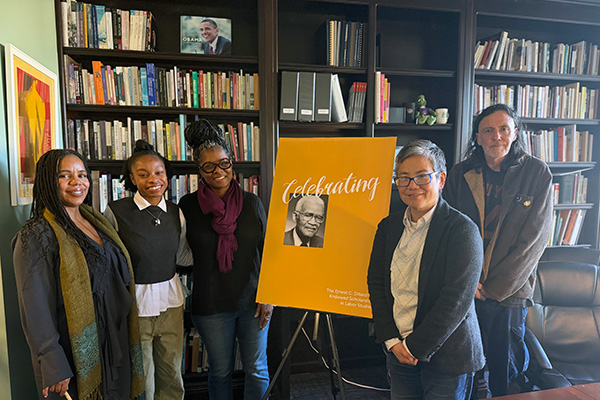 Scholarship recipients Walton and Bridget pose with Dee Bradford, Amy Sueyoshi and John Logan in front of a poster commemorating the scholarship’s namesake, Ernest C. Dillard.