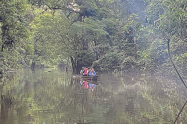 Students canoe down a river surrounded by forest in Ecuador
