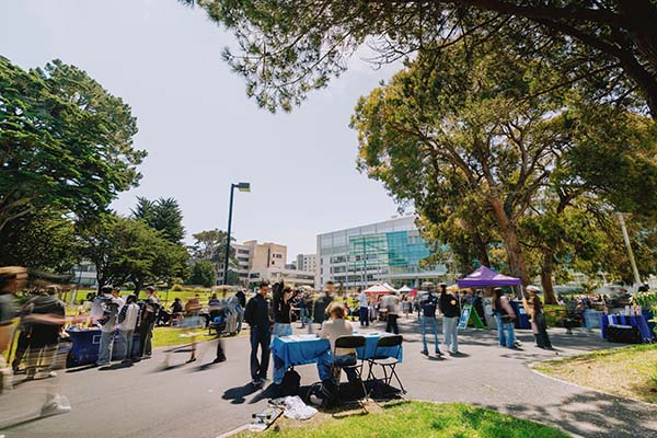 SFSU community members walk through campus during an outdoor tabling event.