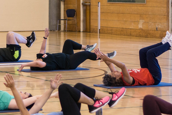 Group fitness class stretching on yoga mats in a gym.
