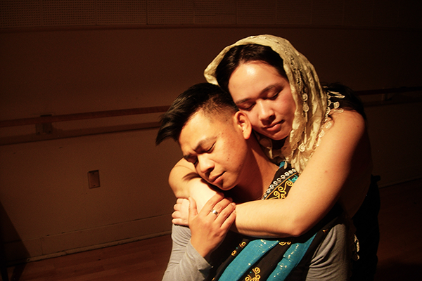 Two actors embrace under a spotlight.