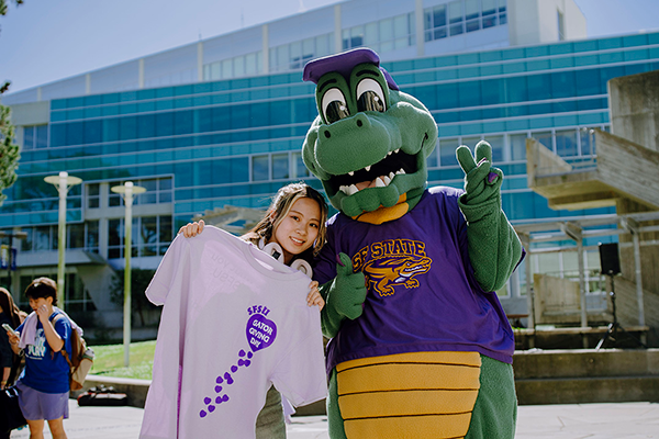 Alli the Gator and a student showing Gator Giving Day shirt