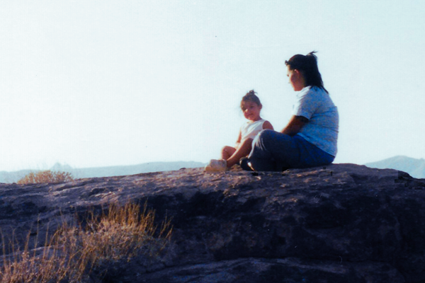 a child and a woman sitting on a hill mound.