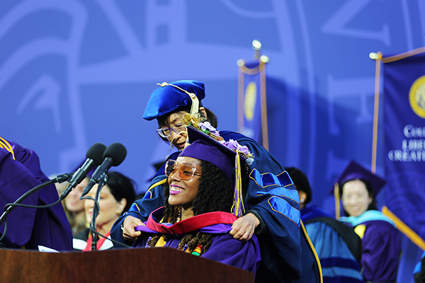 College dean places academic hood on exceptional graduating Gator during commencement