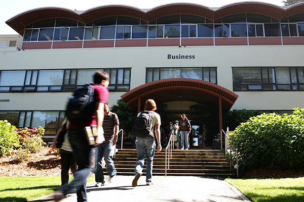 Students walking to the front of Lam Family College of Business building doors