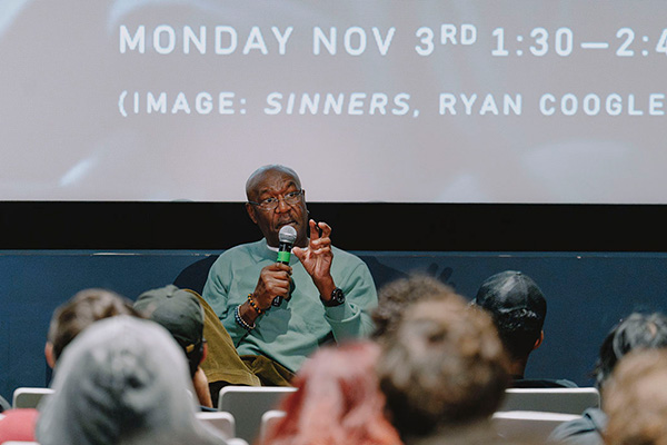 Award winning actor and SFSU alumnus Delroy Lino speaking into a mic 