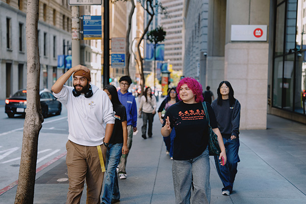 SFSU students walk along a sidewalk in San Francisco’s Financial District.