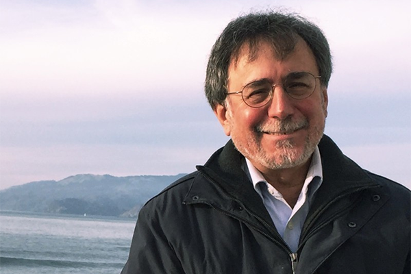 David Olsher smiling, with the ocean and mountains in the background