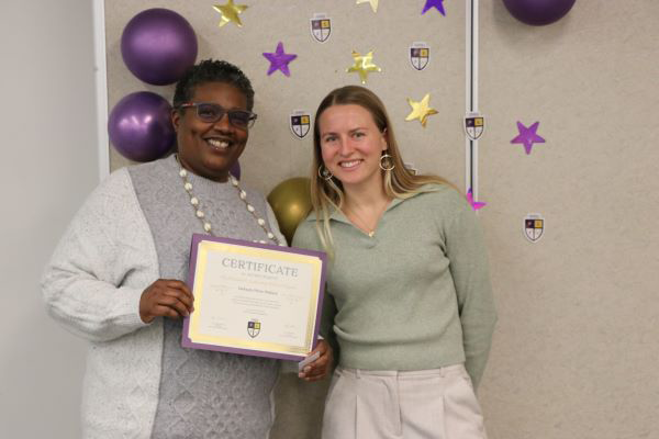 Kylie Schneider smiles and poses with an honoree of the President’s Leadership Fellows Program, who holds their certificate of completion.