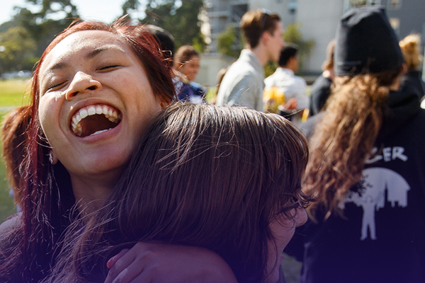 two students smiling and embracing