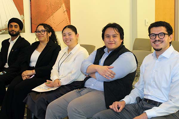 SFSU students interning at SF Federal Credit Union sit together and smile at the camera.
