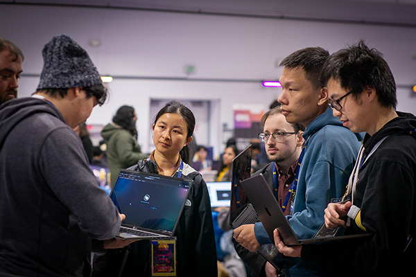 SFHacks participants collaborate in a group with laptops.