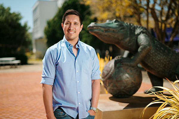 Frankie Sanchez stands and smiles in front of the Gator Spirit Statue.