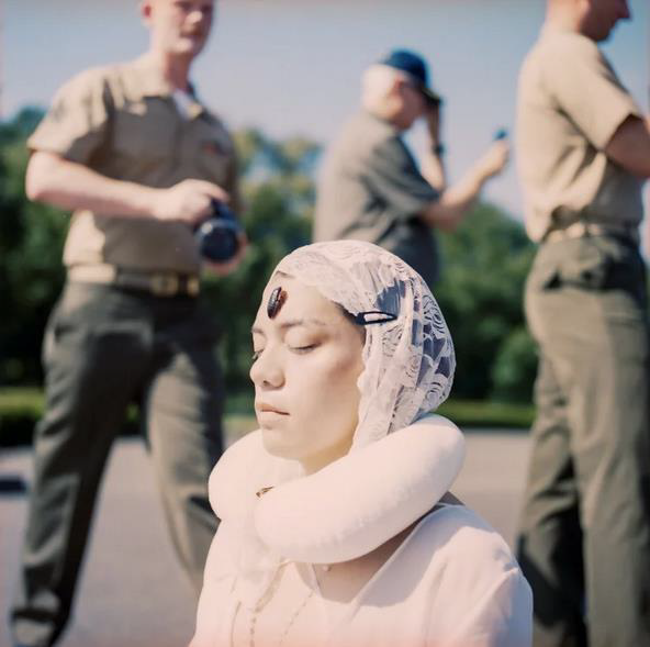 woman wearing hijab sits in protest against men in uniform