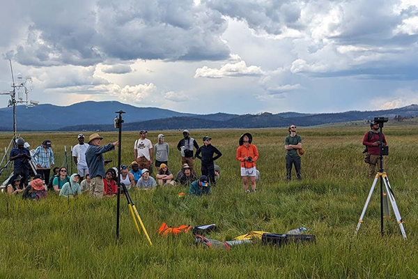Students and professors in a field looking at the sky