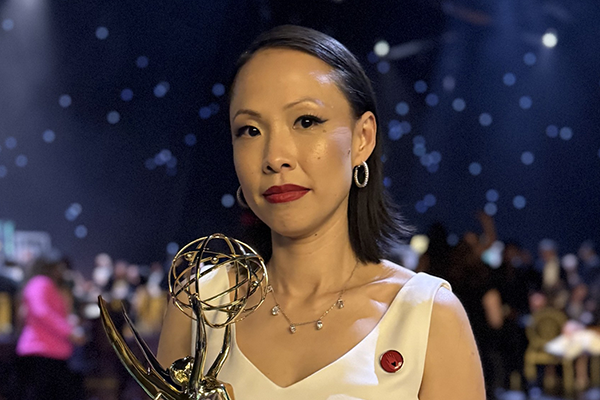 Teng Poh Si holds an Emmy award and looks into the camera