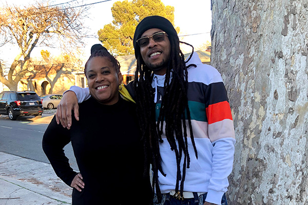 SFSU student Theresa Thompson smiling with her son, Marcus Angelo Bryant, in front of a residential street.