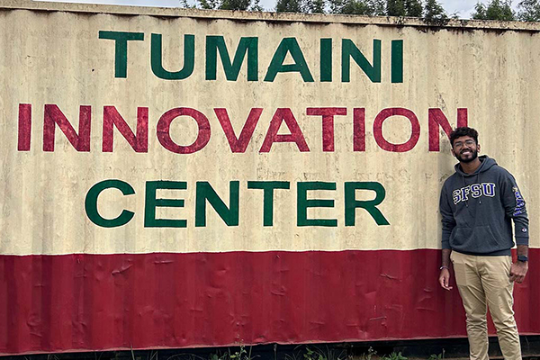 Vasav Juthan Tumaini smiling in front of the "Tumaini Innovation Center"