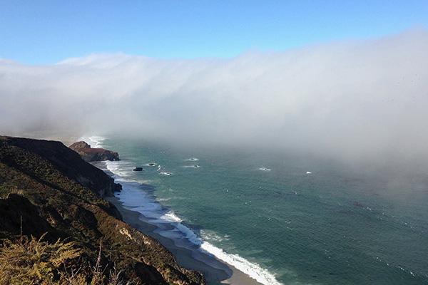 Fog rolling in from the ocean along the rocky northern California coast.