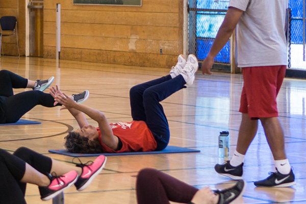 Members of the FitPlus program participate in a group workout on mats in the gym.
