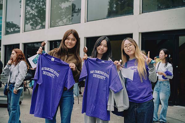 Three students holding up their pinning ceremony sfsu shirts